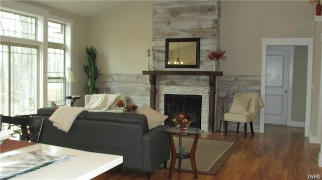 living room with dark wood-type flooring and a stone fireplace