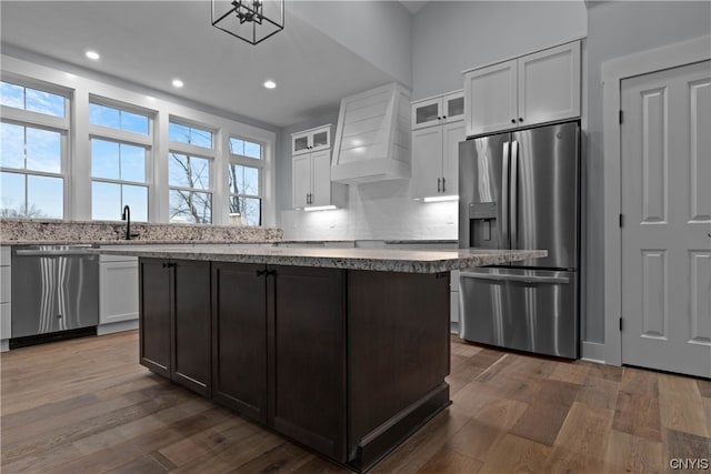 kitchen featuring premium range hood, a center island, white cabinetry, dark wood-type flooring, and stainless steel appliances