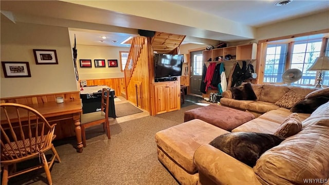 carpeted living room featuring wood walls