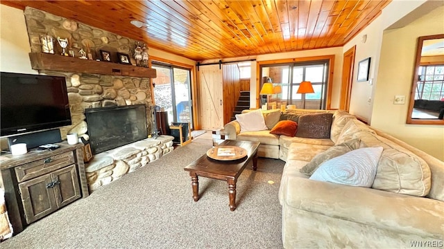 living room with a stone fireplace, carpet floors, and wooden ceiling