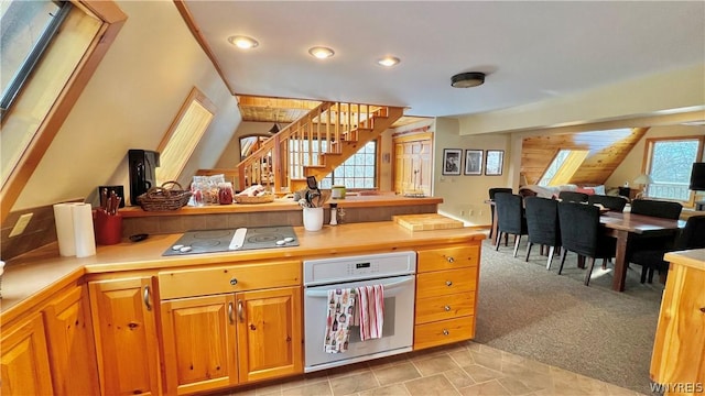 kitchen featuring black electric cooktop, a wealth of natural light, light colored carpet, and white oven