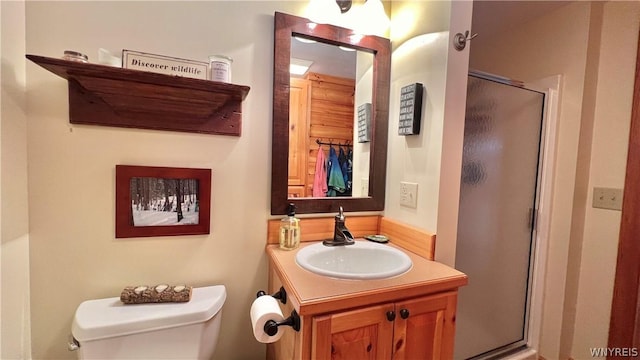 bathroom with a shower with door, vanity, and toilet