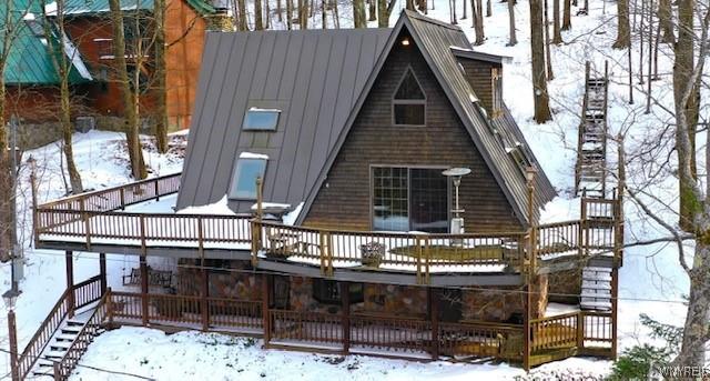 snow covered house with a wooden deck