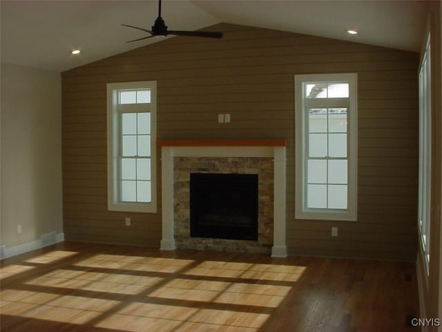 unfurnished living room featuring hardwood / wood-style flooring, lofted ceiling, a fireplace, and wooden walls