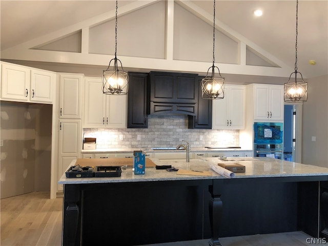 kitchen featuring pendant lighting, high vaulted ceiling, light wood-type flooring, and white cabinetry