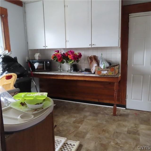 kitchen with tasteful backsplash, white cabinets, and light tile floors