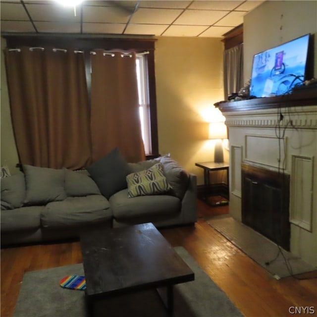 living room featuring wood-type flooring and a drop ceiling