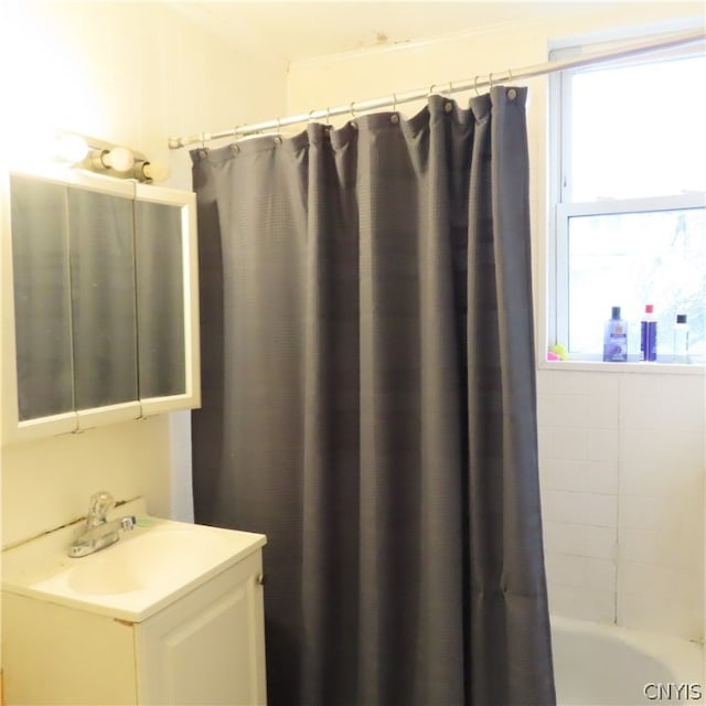 bathroom featuring a healthy amount of sunlight, shower / bathtub combination with curtain, and vanity