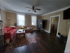 living room featuring ceiling fan, dark wood-type flooring, and a wood stove