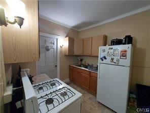 kitchen with stove, ornamental molding, and white refrigerator