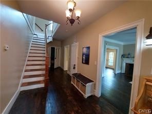 stairs featuring a notable chandelier and dark wood-type flooring