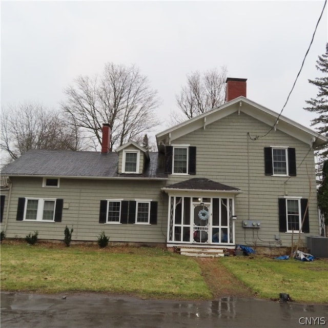 view of front of home featuring central AC unit, a front yard, and a sunroom