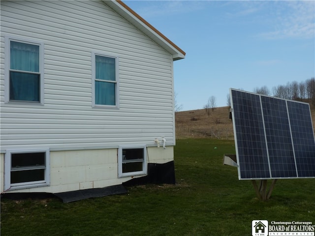 view of side of property featuring solar panels and a lawn