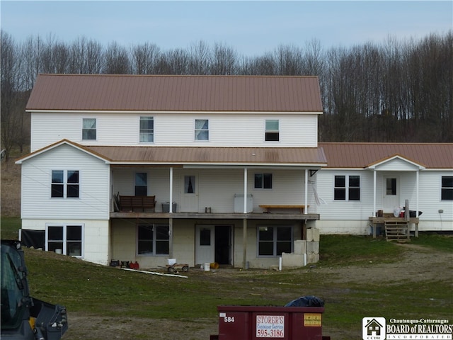 rear view of property featuring a balcony and a yard