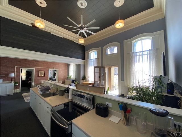 kitchen with stainless steel electric range oven, pendant lighting, ceiling fan, sink, and white cabinetry