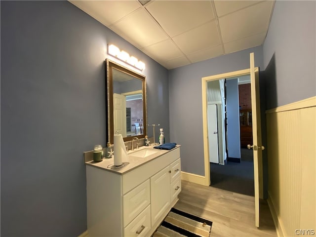 bathroom featuring hardwood / wood-style floors, a drop ceiling, and large vanity