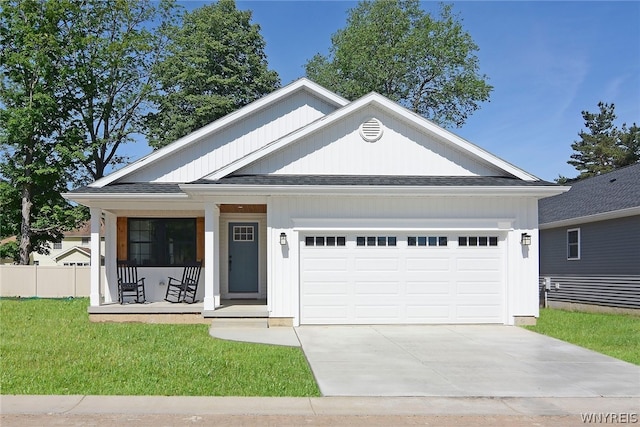 view of front of house with a front lawn, covered porch, and a garage