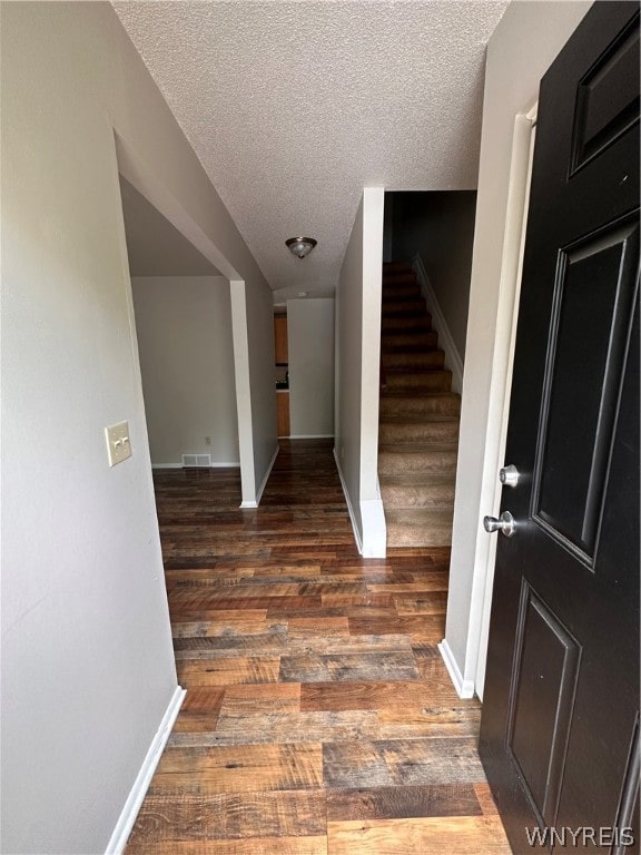 corridor featuring dark hardwood / wood-style flooring and a textured ceiling