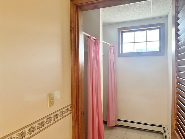 bathroom featuring a textured ceiling, a baseboard heating unit, and tile flooring