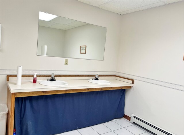 bathroom featuring tile flooring, baseboard heating, a drop ceiling, and double sink vanity