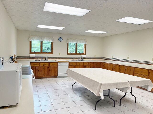 kitchen featuring light tile flooring, white appliances, a drop ceiling, and a wealth of natural light