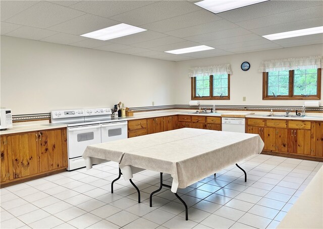 kitchen featuring light tile flooring, sink, and white appliances