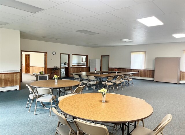 dining space featuring a paneled ceiling, dark carpet, and a baseboard radiator