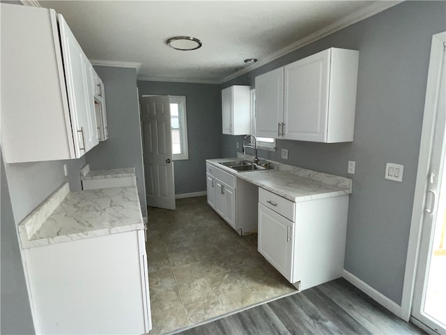 kitchen with light hardwood / wood-style floors, white cabinetry, ornamental molding, and sink