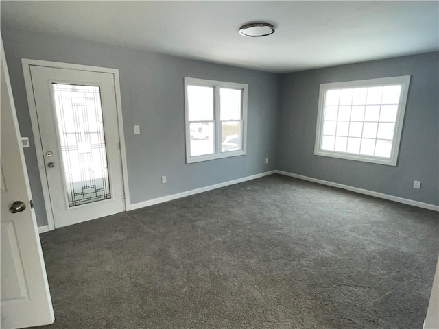 unfurnished room featuring plenty of natural light and dark colored carpet