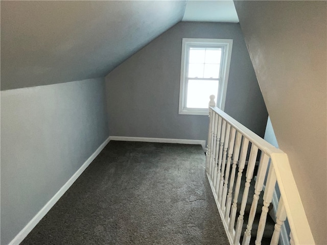 additional living space featuring dark carpet and vaulted ceiling