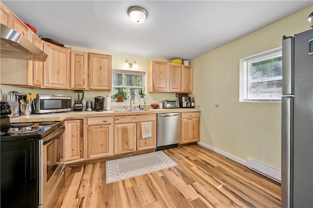 kitchen featuring plenty of natural light, wall chimney exhaust hood, appliances with stainless steel finishes, and light wood-type flooring