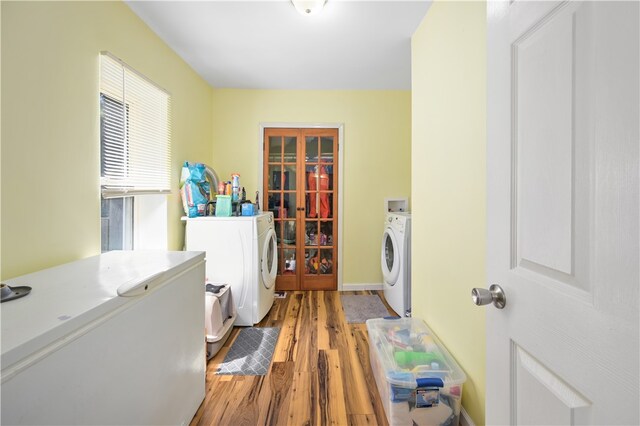 clothes washing area with washing machine and clothes dryer and light hardwood / wood-style floors