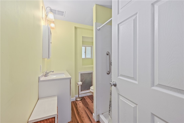 bathroom featuring walk in shower, toilet, hardwood / wood-style flooring, and vanity with extensive cabinet space