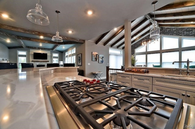 kitchen with sink, vaulted ceiling with beams, a water view, stovetop, and plenty of natural light