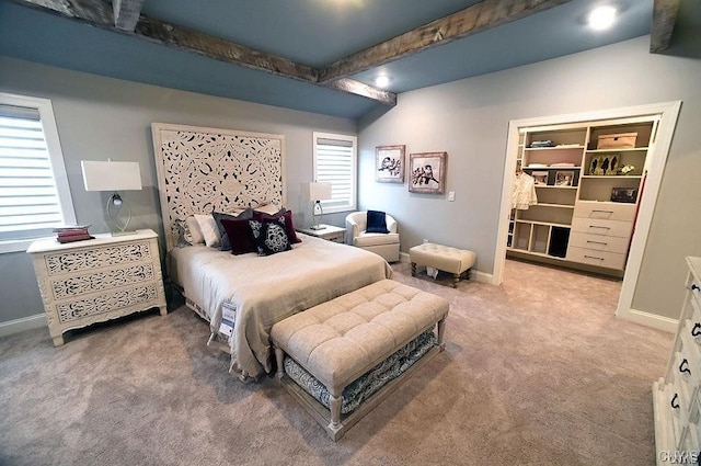 carpeted bedroom featuring beam ceiling and a spacious closet