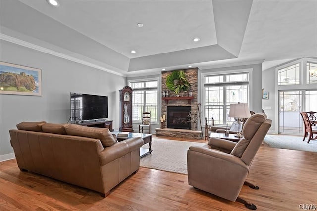 living room featuring light hardwood / wood-style flooring, a raised ceiling, and a fireplace