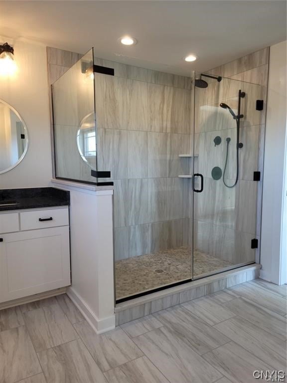 bathroom with a shower with door and vanity