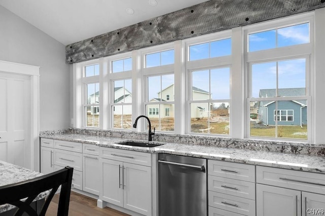 kitchen with sink, white cabinets, light stone counters, lofted ceiling, and hardwood / wood-style flooring