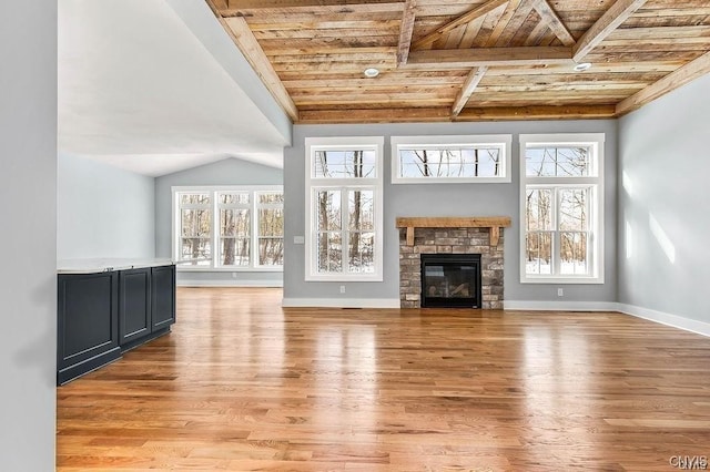 unfurnished living room with a fireplace, light hardwood / wood-style floors, wooden ceiling, and plenty of natural light