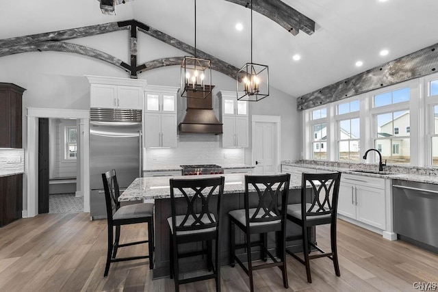 kitchen with stainless steel appliances, white cabinetry, tasteful backsplash, and premium range hood