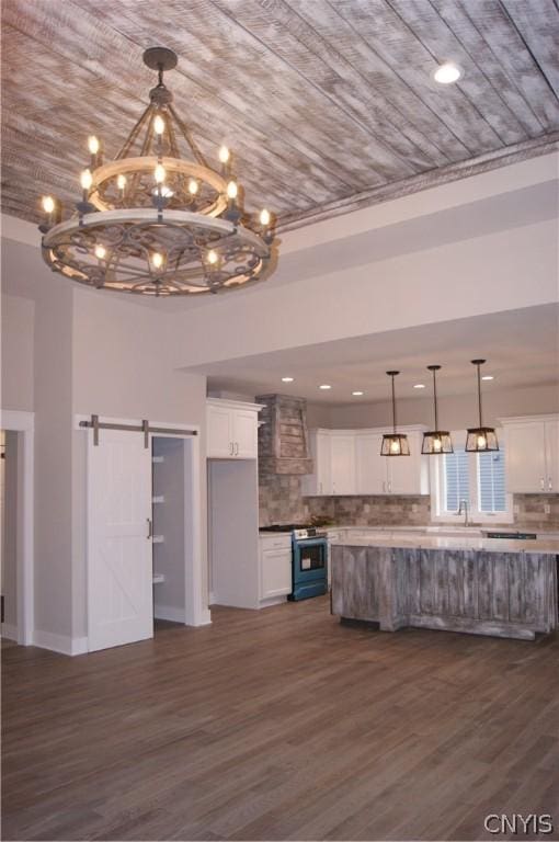 kitchen featuring stainless steel range, a barn door, decorative backsplash, and white cabinetry