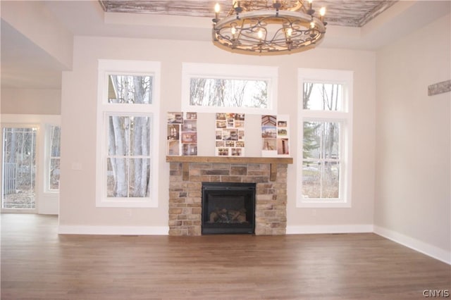 unfurnished living room with an inviting chandelier, plenty of natural light, and a fireplace