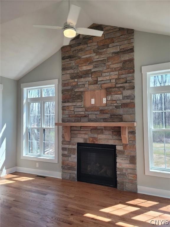 room details with hardwood / wood-style floors, ceiling fan, and a stone fireplace