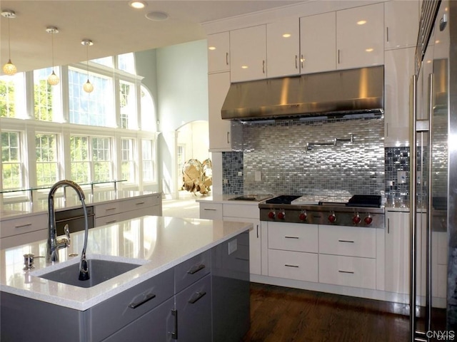 kitchen featuring backsplash, pendant lighting, sink, light stone countertops, and white cabinets