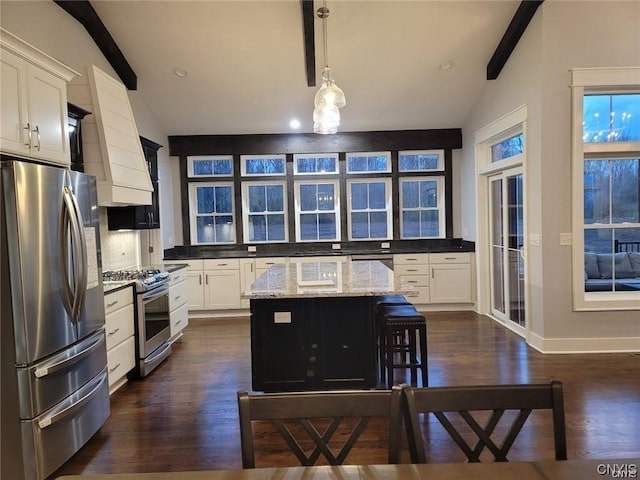 kitchen with stainless steel appliances, a kitchen island, pendant lighting, white cabinets, and light stone counters