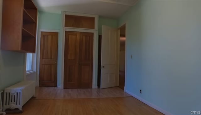 unfurnished bedroom with radiator, light hardwood / wood-style flooring, and a closet