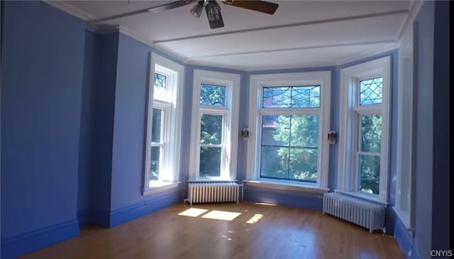 unfurnished room with dark hardwood / wood-style flooring, ceiling fan, radiator, and ornamental molding