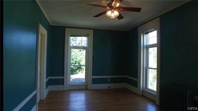 spare room featuring dark hardwood / wood-style floors, ceiling fan, and radiator heating unit