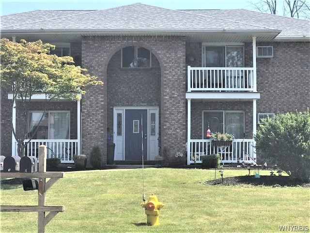 view of front of house with a balcony and a front yard