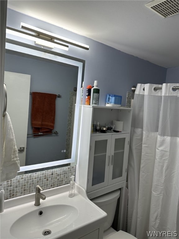 bathroom featuring toilet, tasteful backsplash, and vanity